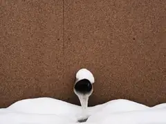 Ice built up on an outdoor pipe in the snow